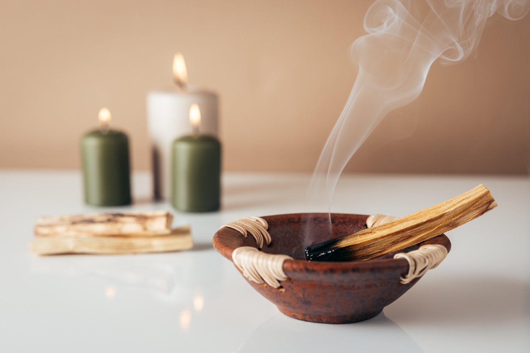 Palo santo burning stick and candles in background